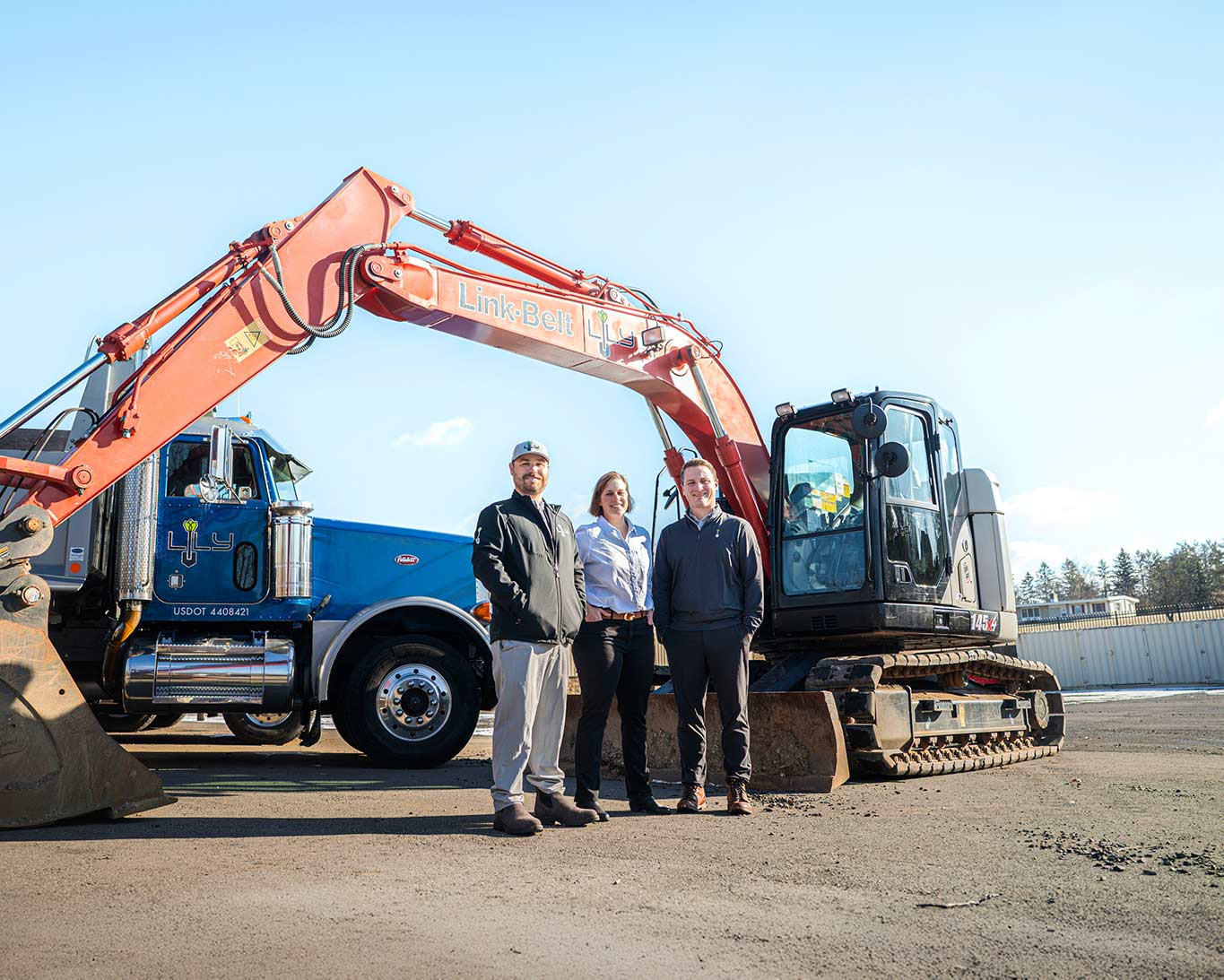 Lily Project Services team members positioned beside large excavation equipment at an active project site.